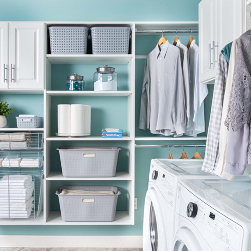 Select laundry room with washer and dryer unit, laundry baskets, hanging clothes, detergent with blue walls.