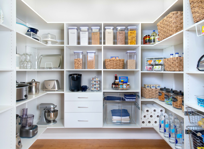 Select walk-in pantry with small accessories, food, paper towel on shelves with neutral walls.