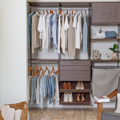Driftwood Live Reach-in Women's Closet with neutral and blue clothing and accent chair in corner.