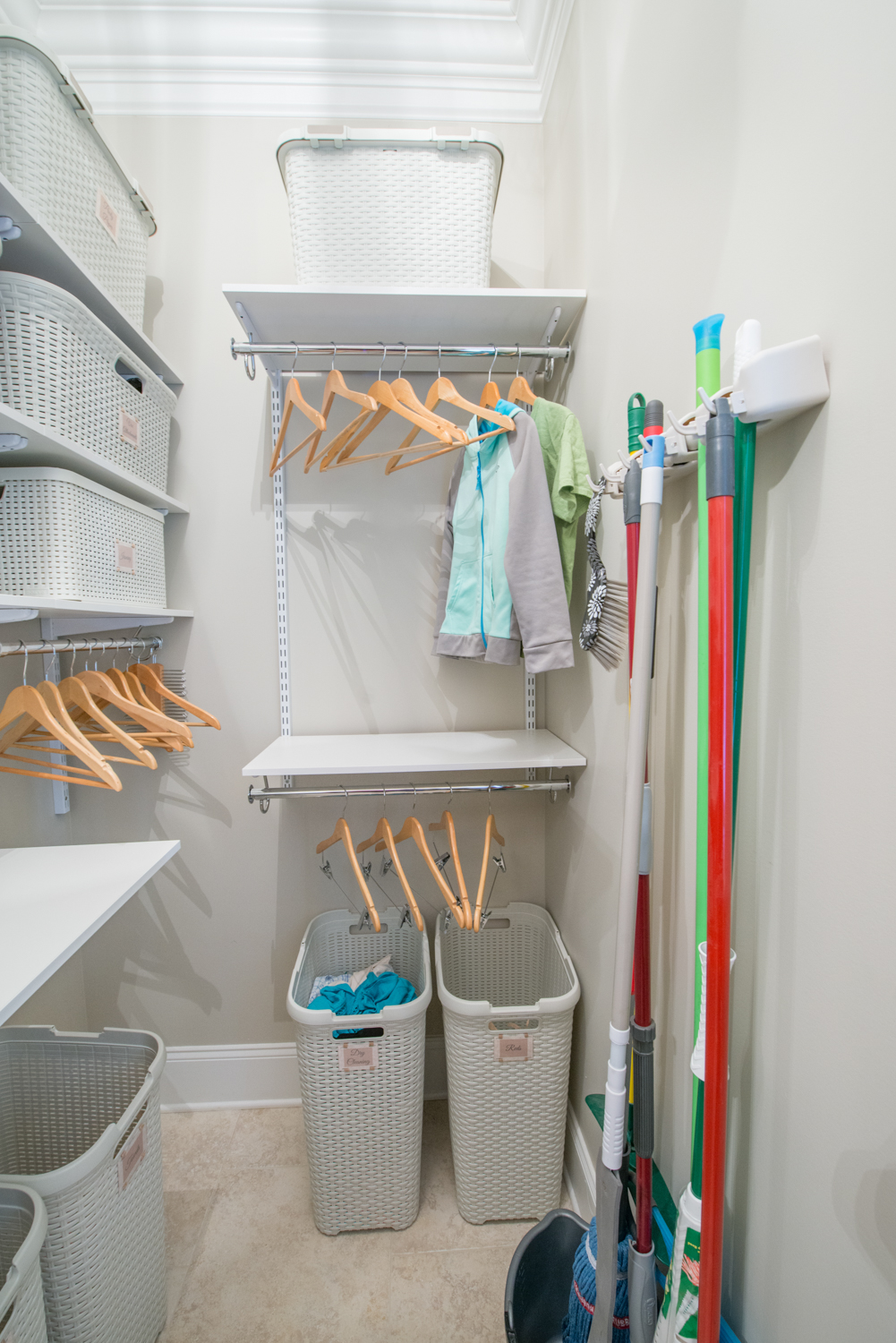 freedomRail Cleaning Closet in White with laundry bins, empty hangers, and mops.