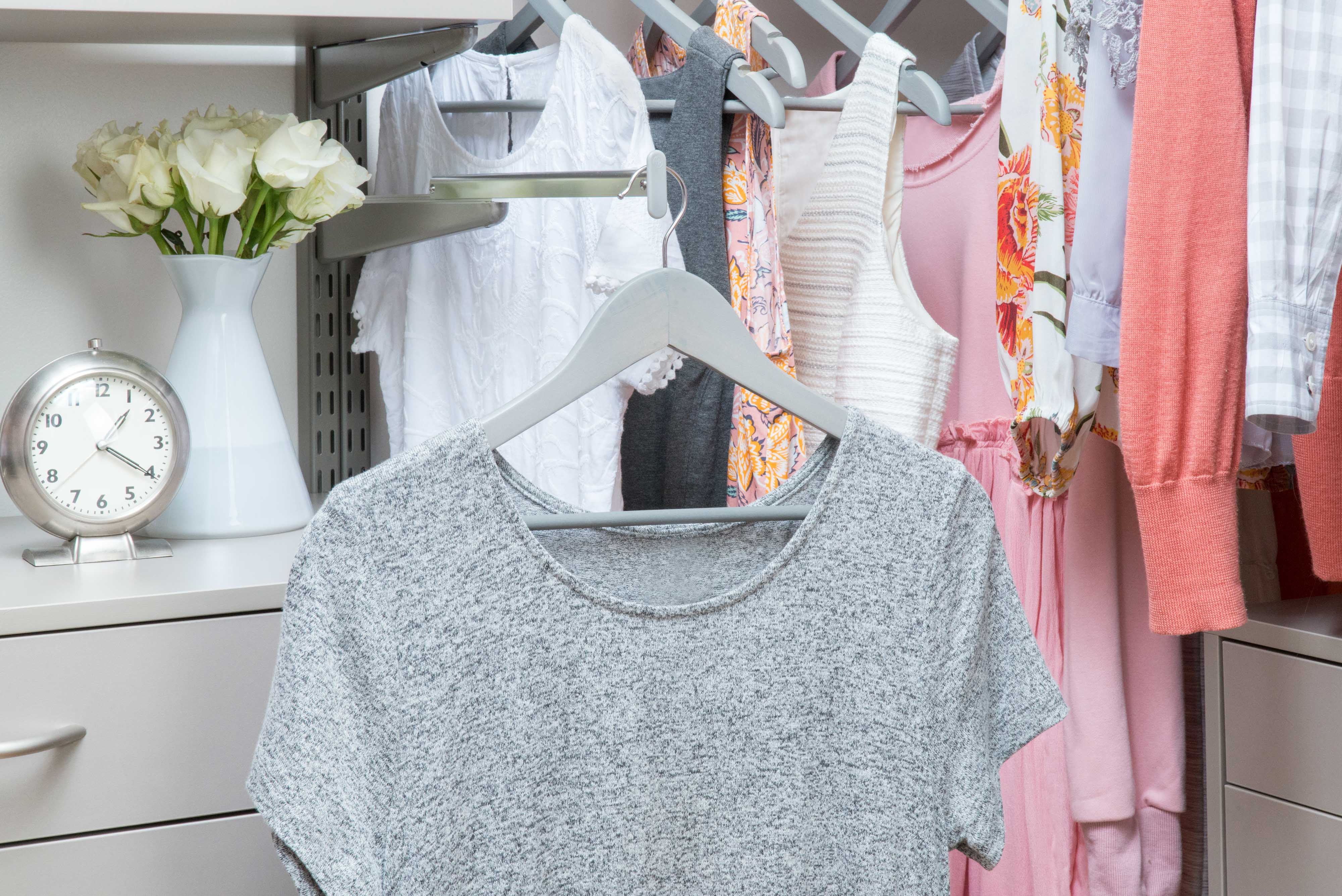 freedomRail Walk-in Closet in Century Gray with women clothing, alarm clock, and flowers.