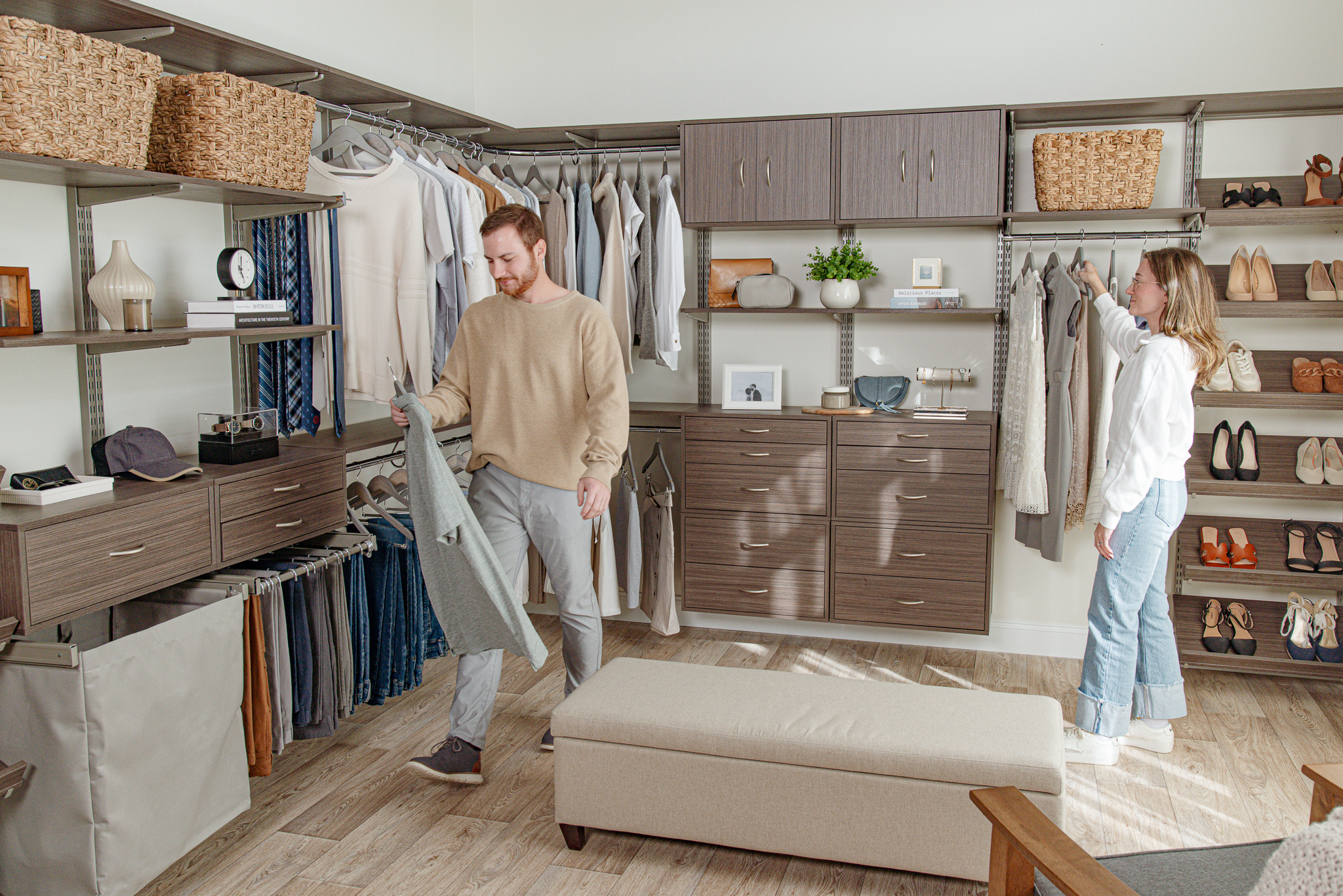 freedomRail Walk-in Closet in Driftwood Live with male and female models grabbing clothes with neutral background.