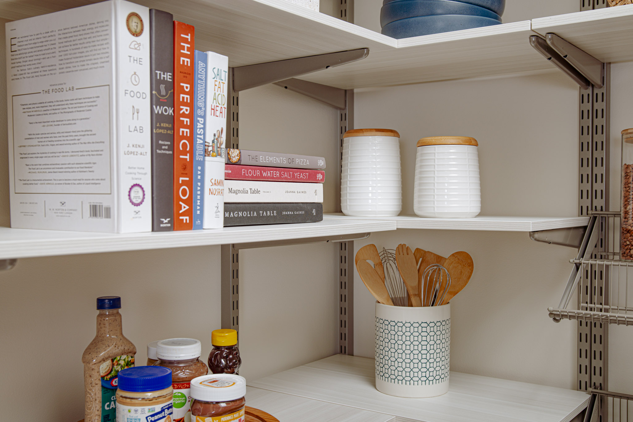 freedomRail Walk-in Pantry in Snowdrift Live with cookbooks, wooden utensils, and canned goods.