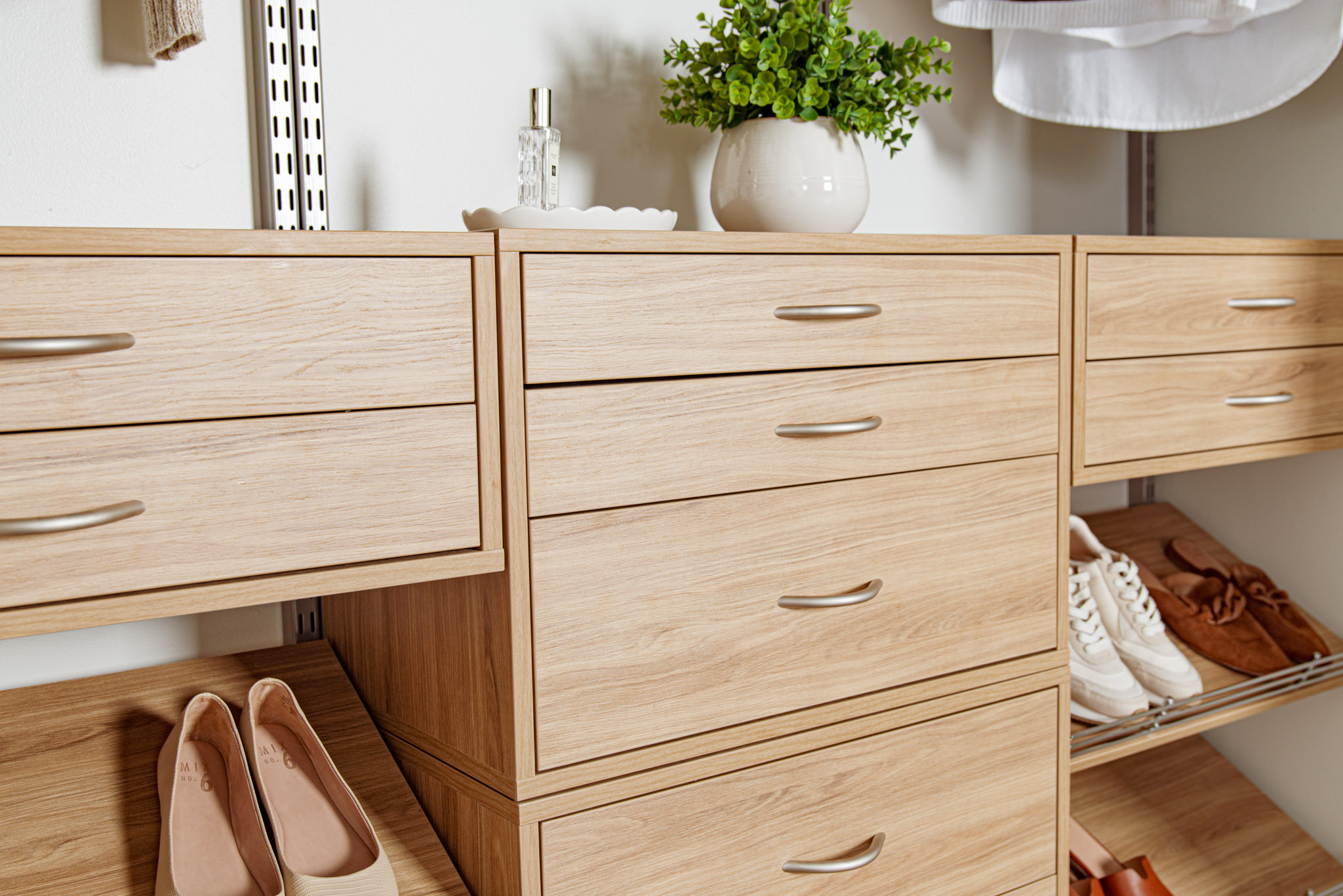 freedomRail_Bedroom_BlondeOak Close Up of drawer boxes with jewelry, plant, shoes and neutral background.