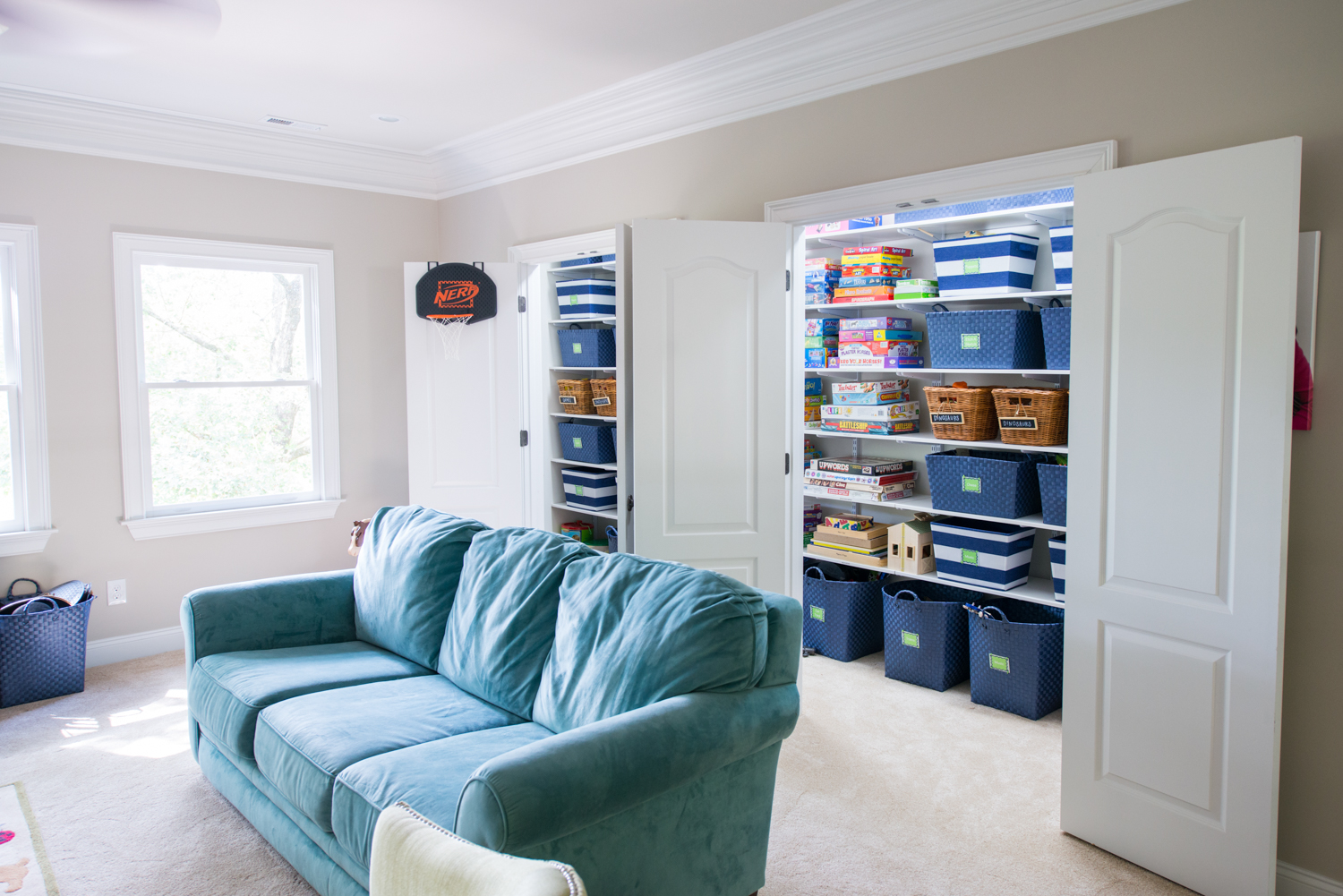 Game room with freedomRail closet with blue couch and board games.