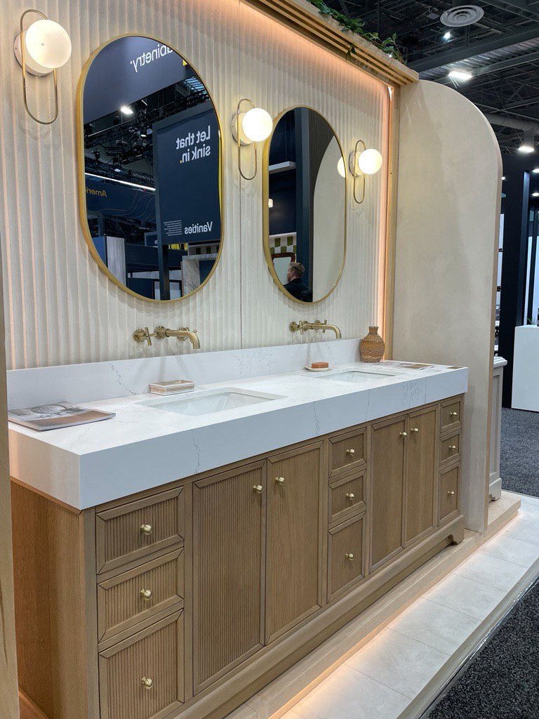 Bathroom Vanity Display at IBS 2025 with fluted cream walls and fluted wooden cabinet fronts.