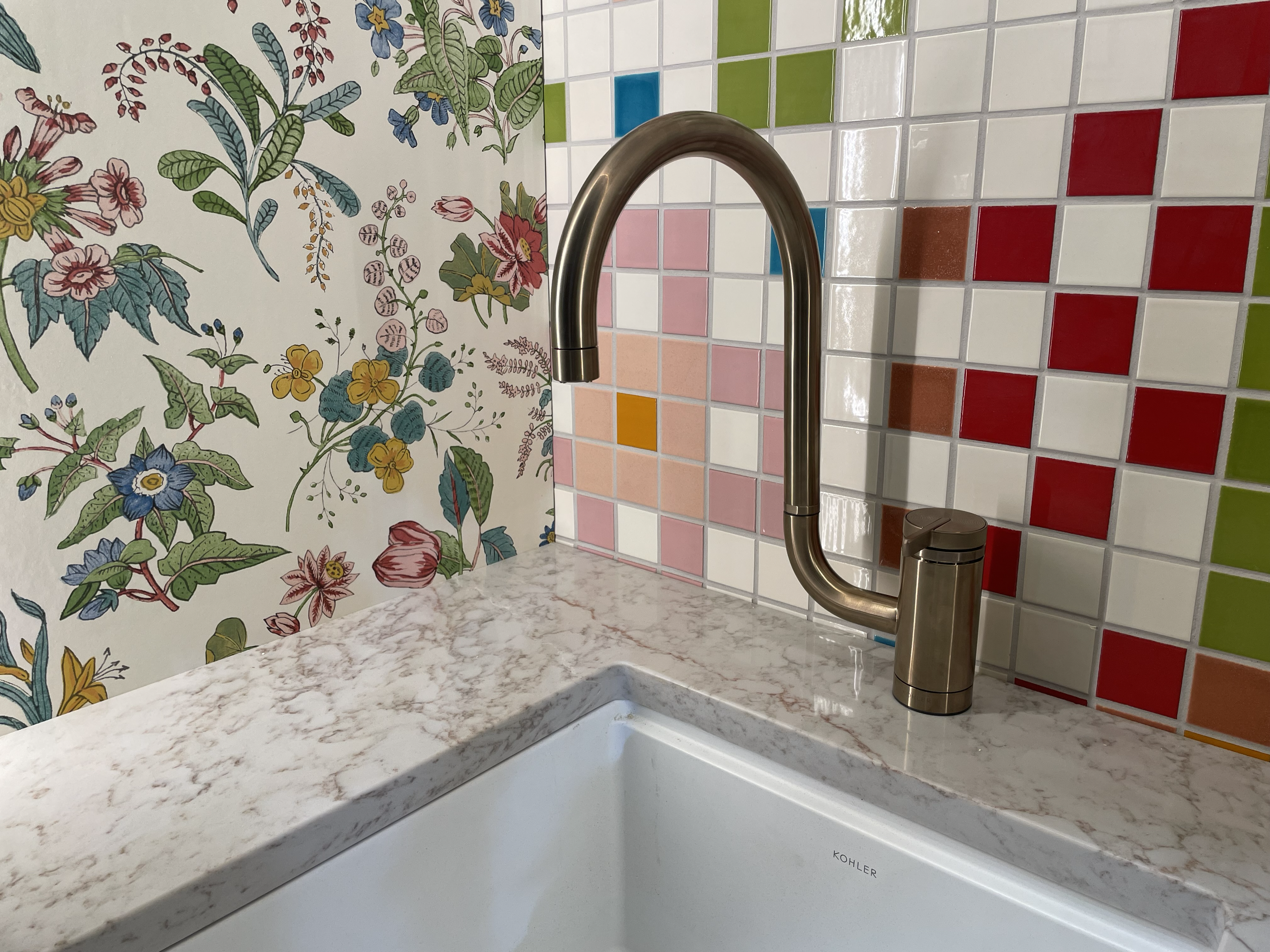 Counter Display at IBS 2025 showing floral wallpaper next to multicolored tiles of pinks, greens, reds, blues, and white.