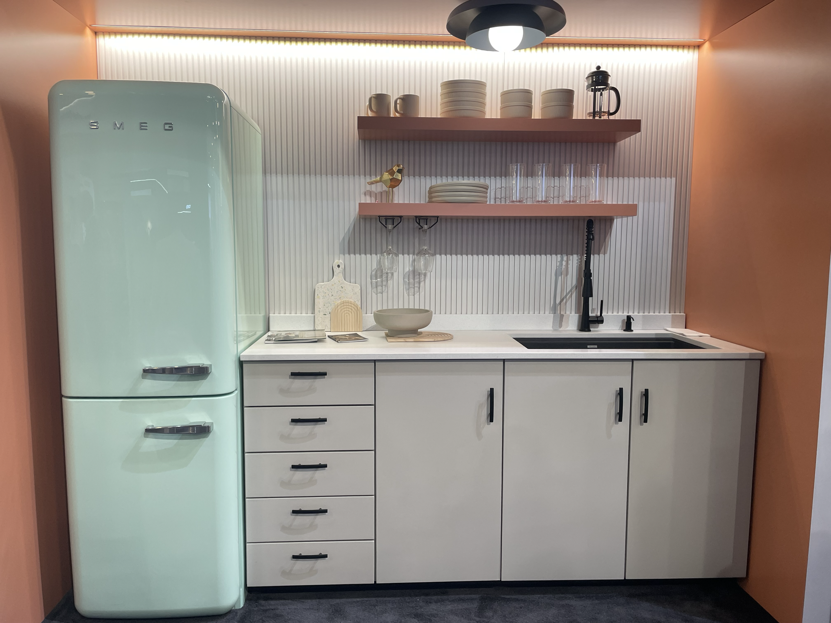 Kitchen Display at IBS 2025 with teal SMEG refrigerator, fluted wall, and burnt orange walls.