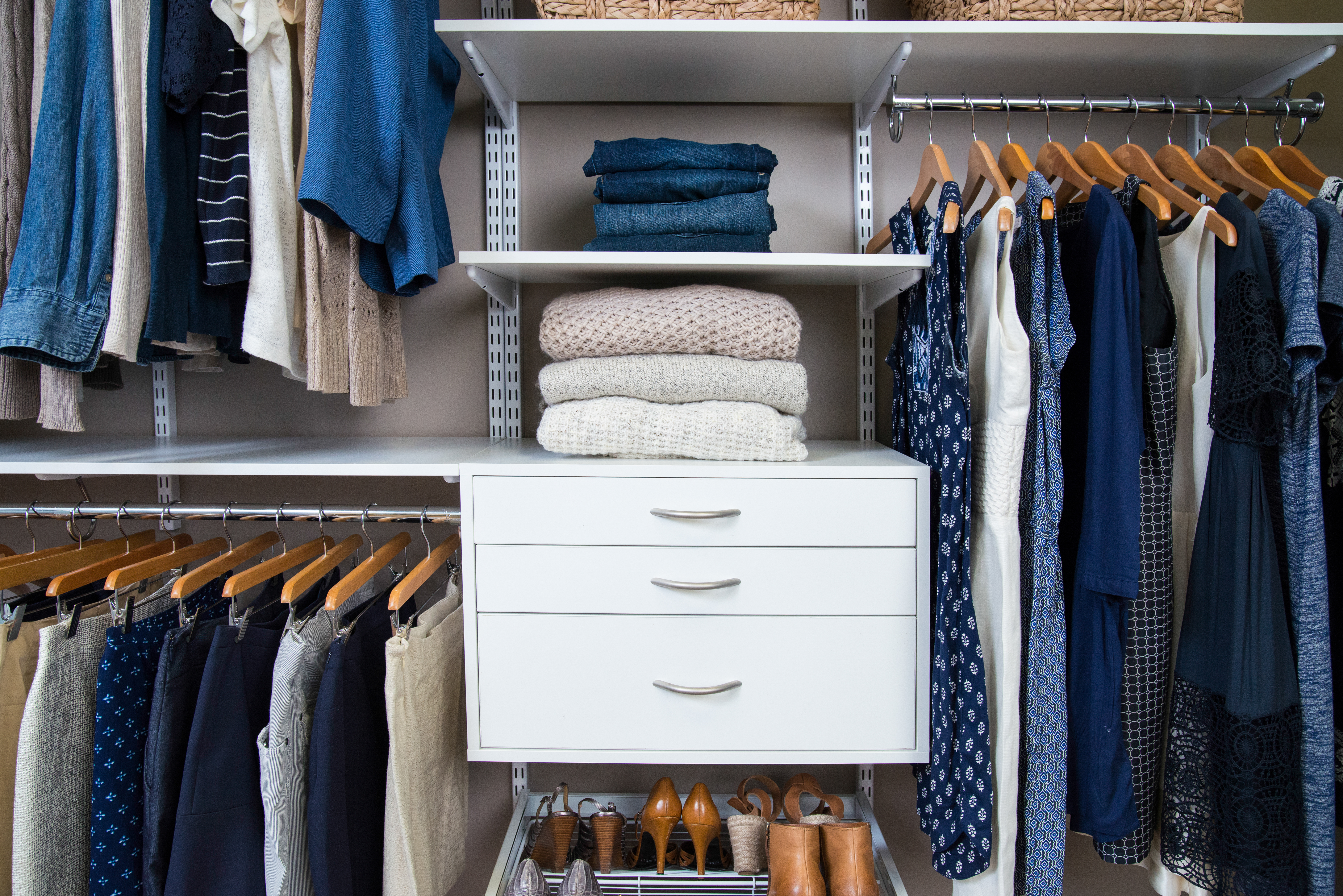 freedomRail reach-in closet in White with women's blue hued clothing, drawer, and storage.
