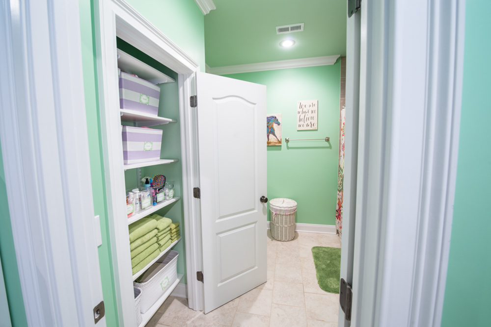 freedomRail Linen Closet in White with towels, toiletries, and storage baskets.