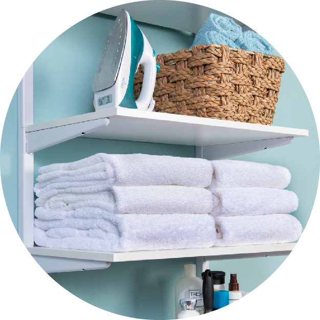 White freedomRail linen closet propped with towels, a basket and a iron.