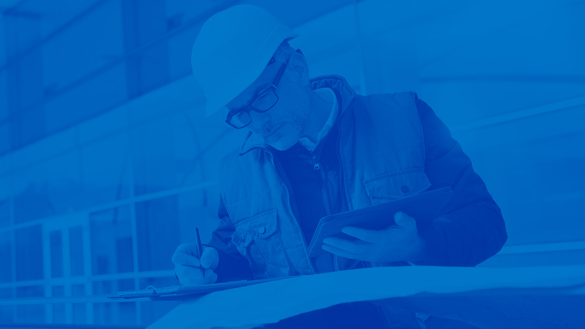 Male general contractor looking at plans. Blue overly over image.