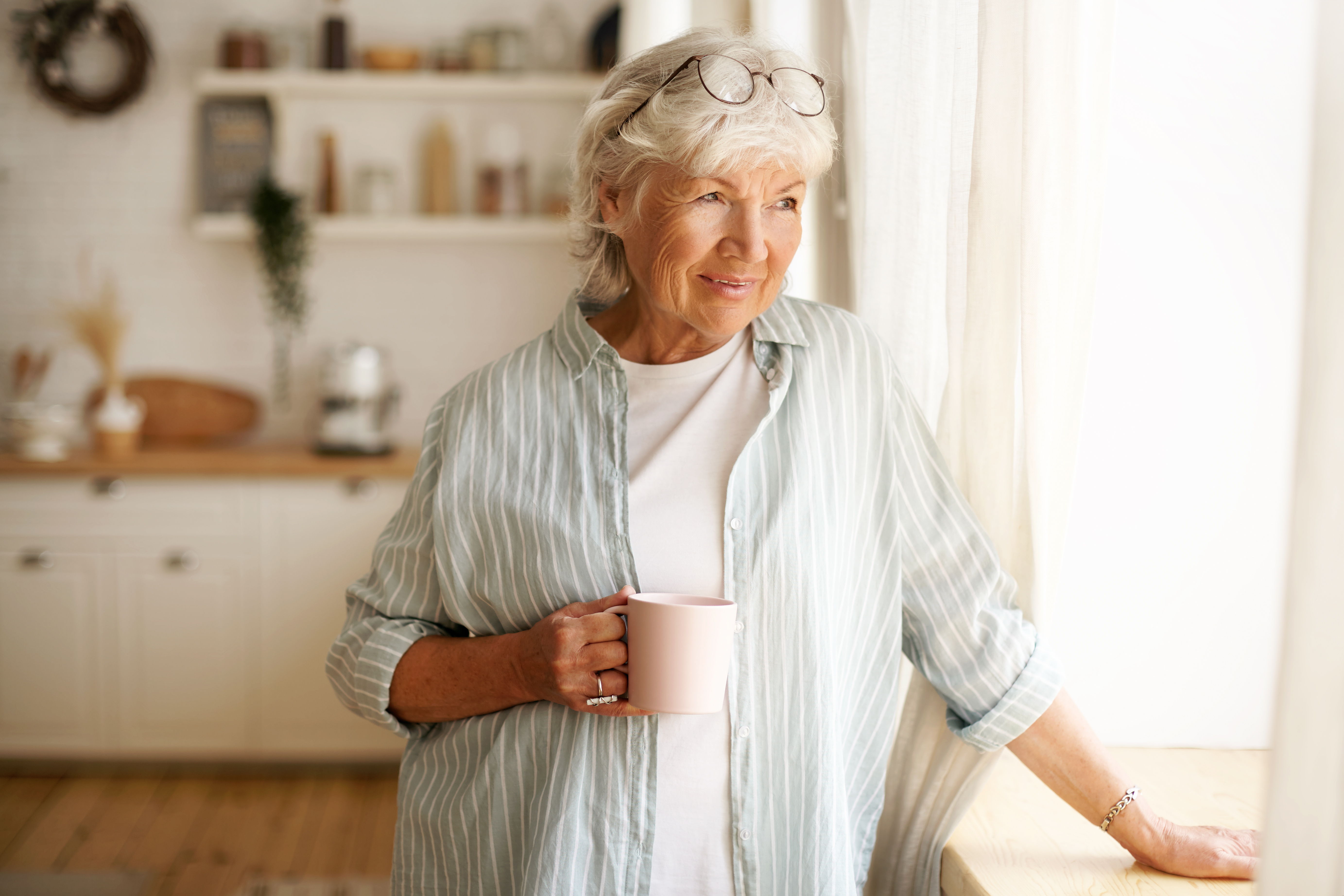 Elderly woman standing inside of her suite an an assited living facility.