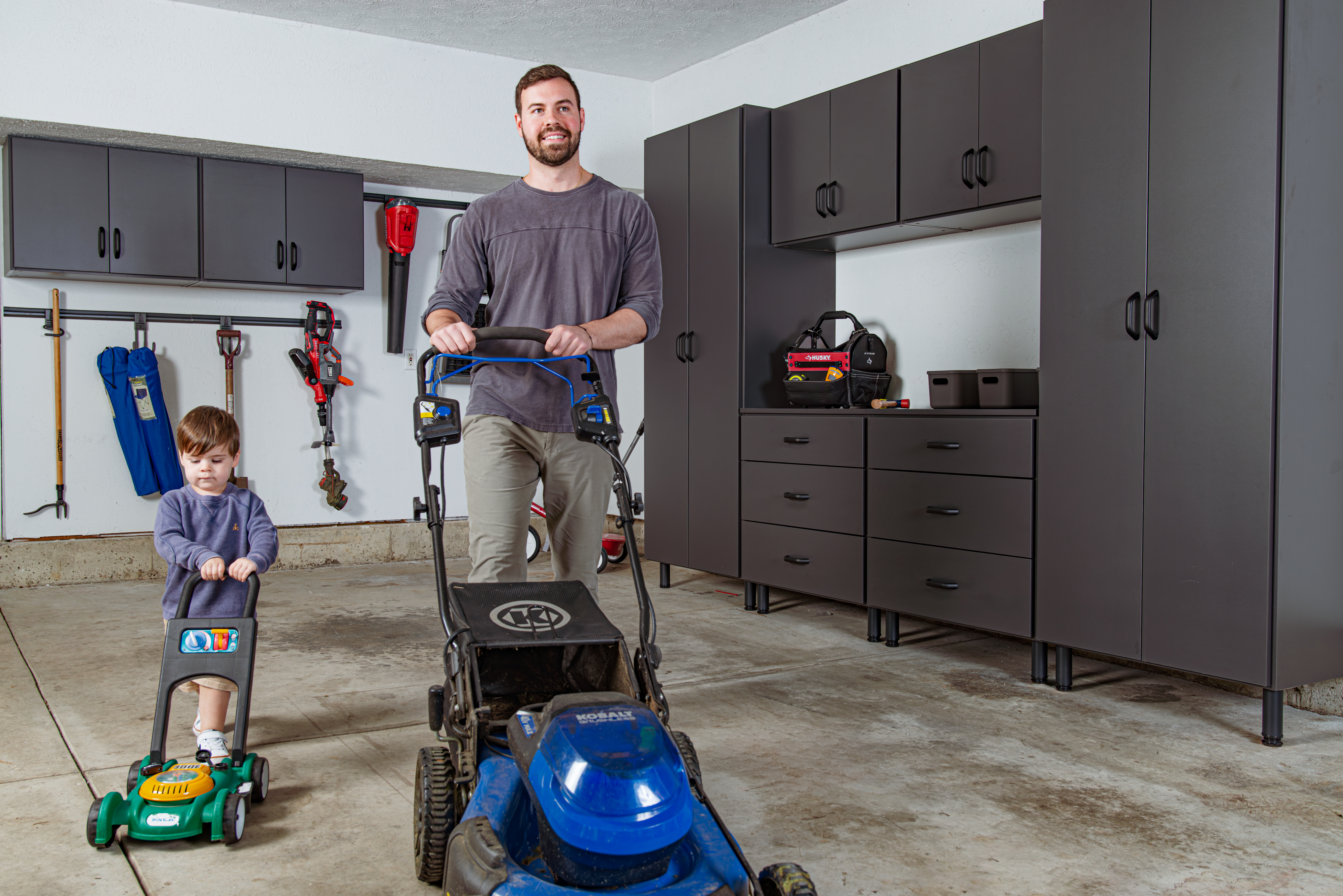 freedomRail EDGE Garage line. Adult with child pushing lawn mower.